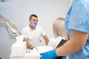 Obraz premium beautiful caucasian girl with a toothache sits in a dental chair. A professional male dentist helps his female patient in pain. painful help in treatment.