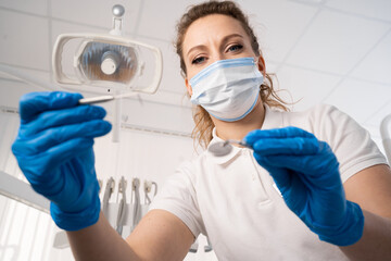 Dentist woman alone holding dental instruments, looking at the camera. Personal or patient point of view, POV. dental treatment concept.