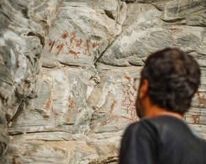 homem olhando para pinturas rupestres com 9 mil anos no Sítio Arqueológico Xiquexique, em...