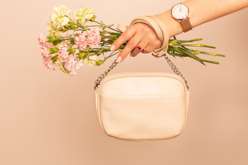 Fashion spring accessories - white handbag (purse), gold watch and flowers on nude background - obrazy, fototapety, plakaty