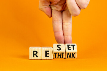 Rethink and reset symbol. Businessman turns wooden cubes and changes the concept word Rethink to Reset. Beautiful orange table orange background. Business rethink and reset concept. Copy space.