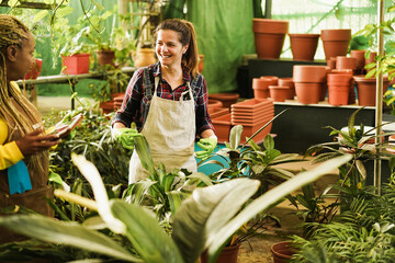 Obraz premium Multiracial women working inside green glasshouse garden market - Focus on right female face