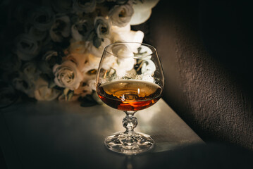 Glass and bouquet. Cognac, whiskey, alcohol. Wedding bouquet and drink