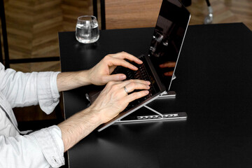 Man works on laptop. Laptop on the black table