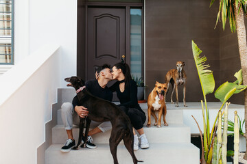 Young couple kissing while sitting with their dogs