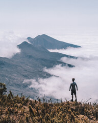 silhueta de homem não identificado no alto do Pico da Bandeira, com montanhas e mar de nuvens ao...