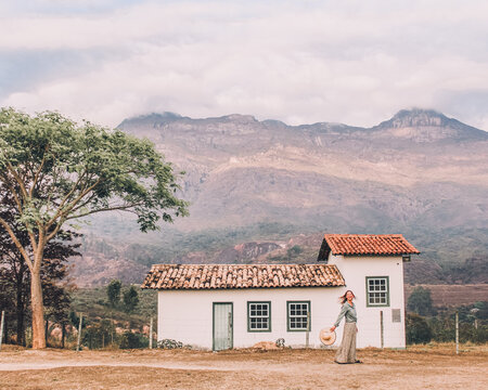 mulher caminhando em frente &agrave; casebre em frente &agrave; montanhas em Catas Altas, minas Gerais