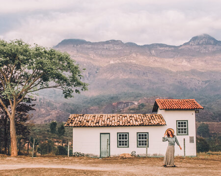 mulher caminhando em frente &agrave; casebre em frente &agrave; montanhas em Catas Altas, minas Gerais