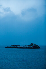 Small black island on deep blue sea - ocean and sky - Lofoten, Norway