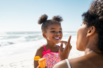 Lovely black mother applying sunscreen on cute little black girl - 492004891