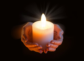 Women's hands holding a candle