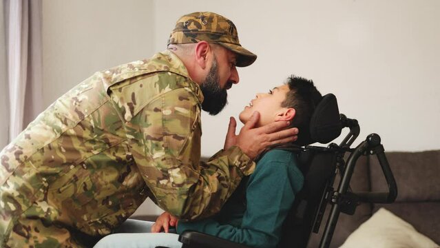 Military soldier father kissing kid son with disability on wheelchair during home return - Family love Us army