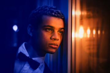 Street portrait of handsome young man of African American origin on a nice evening, blue and orange neon lights