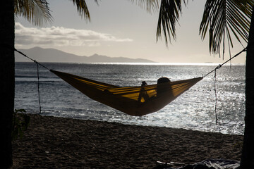 Fille en train de se reposer dans un hamac au coucher de soleil sur une île dans les antilles et...