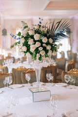 Wedding table decor in white green tones. Wedding table set up in boho style with pampas grass and greenery, soft focus.