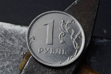 Russian coin with a face value of 1 ruble. and an old working tool. close-up. translation of the...