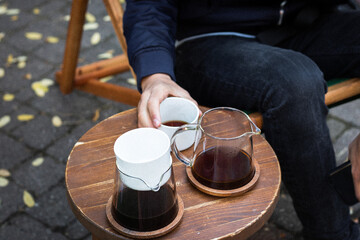 Filter coffee in server and cup with man's arms