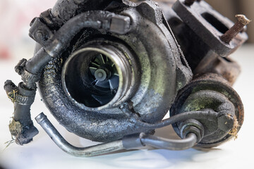 Old and worn car turbo charger. View of the flange on intake with broken nuts or screws. Turbo...