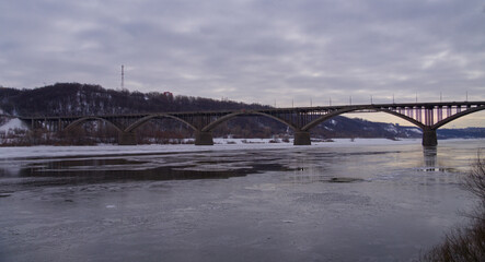Color panoramic photo with an arched multi-span bridge. A road bridge over a large river on which ice will soon go. Architecture of beautiful large bridges