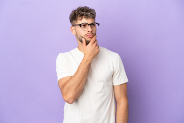 Delivery caucasian man isolated on purple background having doubts