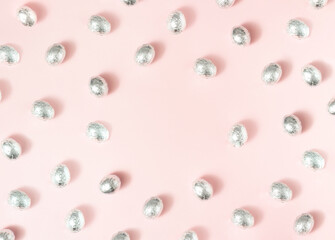 Eggs in aluminum foil on pink background with copy space.