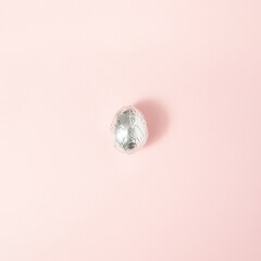 Egg in aluminum foil on pink background. Copy space.