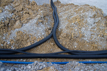 Black corrugated plastic drainage pipes laying in a ditch at a construction site