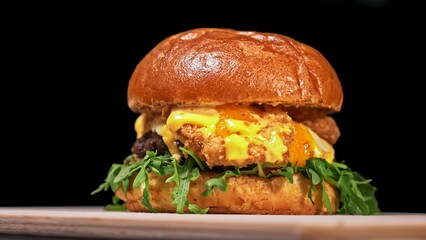 Craft burger is cooking on black background in black food gloves. Consist: sauce, arugula, tomato, red onion rings fries, cucumber, cheese, air bun and marble meat beef. Not made ideal. Looks real