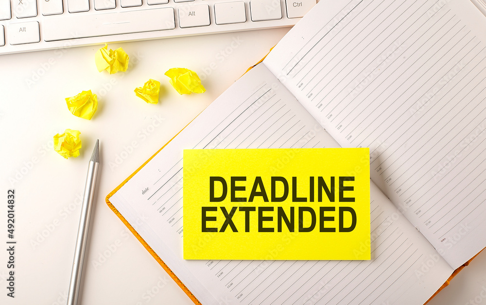 Poster deadline extended text on sticker on the diary with keyboard and pencil