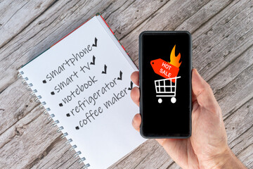 Selective focus of a hand holding a smartphone announcing the hot sale and a wish list in the...