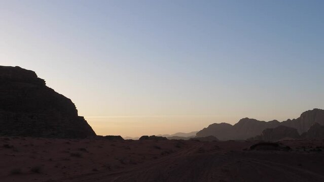 Moving silhouettes of mountains in backlight at sunset in the Wadi Rum desert in Jordan