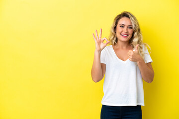 Young Brazilian woman isolated on yellow background showing ok sign and thumb up gesture