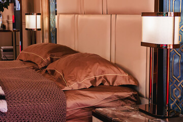 Double headboard with brown pillows and floor lamps