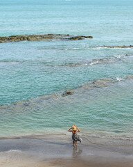 mulher de costas com vestido e chapéu em frente ao mar em Japaratinga, Alagoas