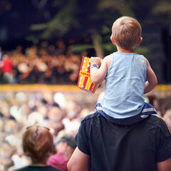 Getting a better view. Rearview shot of a young boy sitting on his fathers shoulders at an outdoor...