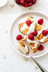 Cottage cheese pancakes in white plate. Syrniki with raspberries and sour cream. Homemade breakfast or lunch.