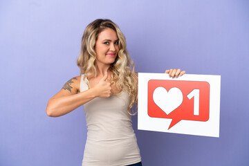 Young Brazilian woman isolated on purple background holding a placard with Like icon with thumb up