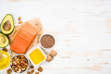 Healthy fats products. Source of Omega 3 and Omega 6. Salmon fish, olive oil, flax seeds oil, avocado and nuts. Top view image at white table.