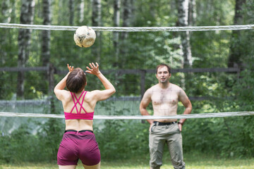 Two friends are playing volleyball on the grass. Activity and fitness hobby concept