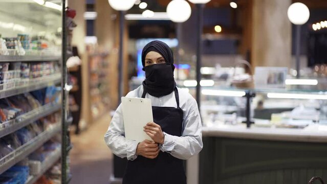 Portrait of supermarket female muslim worker standing with tablet in hands