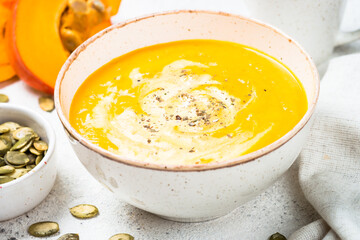 Pumpkin and carrot soup puree with cream and ginger in the craft bowl. Close up.