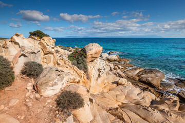 View of the picturesque scene of sea waves crashing on the rocks of a scenic island near resort town in Halkidiki region