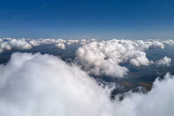 Aerial view from airplane window at high altitude of earth covered with puffy cumulus clouds...