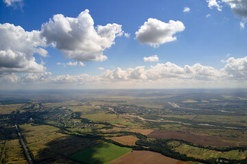 Aerial view from high altitude of earth covered with white puffy cumulus clouds on sunny day