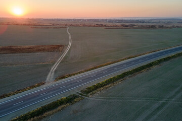 Fototapeta premium Aerial view of empty intercity road with asphalt surface and white markings in evening