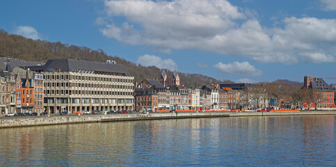 Fototapeta na wymiar Liege, Belgium - March 5. 2022: View over river maas on historical waterfront houses against blue winter sky