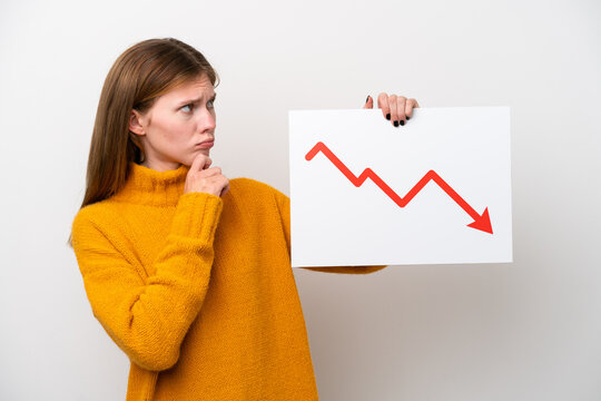 Young English woman isolated on white background holding a sign with a decreasing statistics arrow symbol and thinking