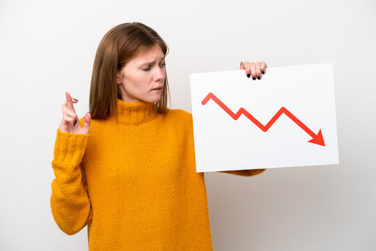 Young English woman isolated on white background holding a sign with a decreasing statistics arrow symbol with fingers crossing