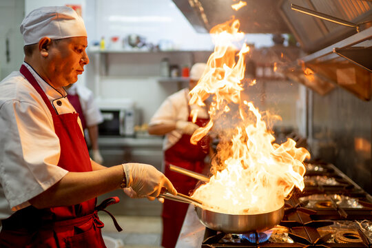 Indian Chef Cooking In Industrial Kitchen With The Burning Pan