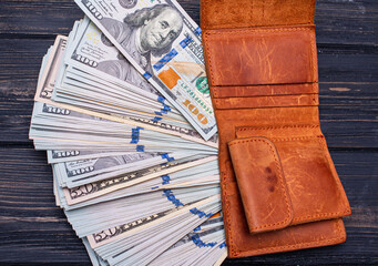 Dollars in a brown wallet on a black wooden background. Financial and business concept.